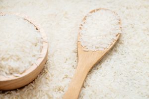 Raw Jasmine rice in wooden bowl  and spoon with grain and seed