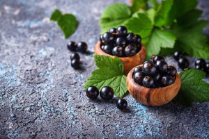 Black currant with leaves in wooden bowls. Selective focus